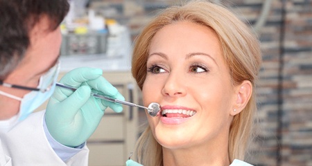 A woman having her teeth examined by a dentist after denture placement