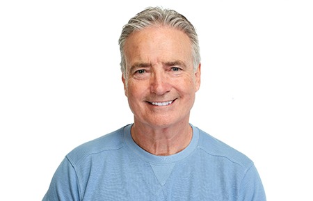 Man in blue shirt smiling with white background
