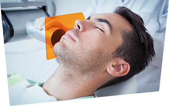 Relaxed man receiving dental treatment under sedation dentistry