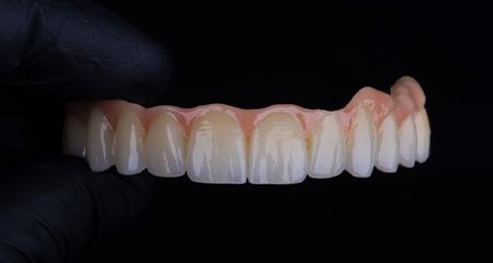 Dentist holding an upper denture on black background
