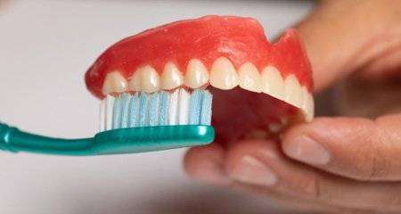 A denture being rinsed with tap water