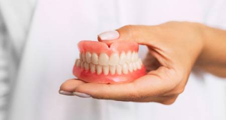 A denture being cleaned with a toothbrush