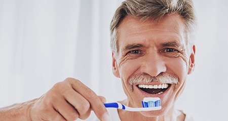 Dentures:Man holding a toothbrush with toothpaste
