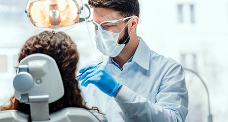 Dentist wearing PPE and smiling while placing a dental crown