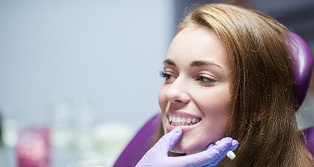Dentist examining patient's smile with purple gloves