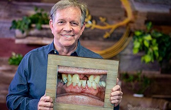 Smiling man with dental implants in Gainesville holding before photo