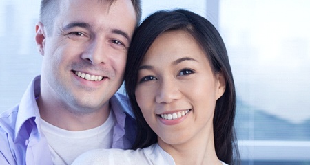 A younger couple smiling after denture tooth replacement