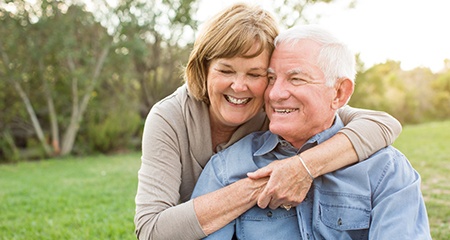 Older couple smiling and hugging outside