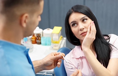 woman with toothache talking to her emergency dentist in Gainesville 