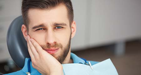 Man with a toothache in Gainesville holding his cheek