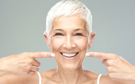 Confident senior woman pointing at her beautiful smile