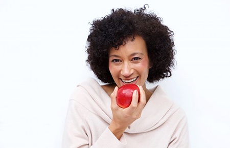 woman biting into a red apple 