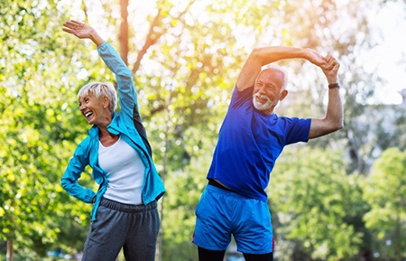 older couple stretching outside before exercising 
