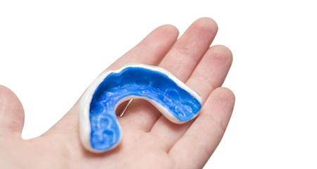 person holding a blue mouthguard in their hand