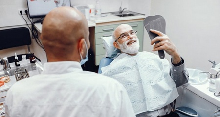 patient with dental implants in Gainesville admiring his smile in a mirror
