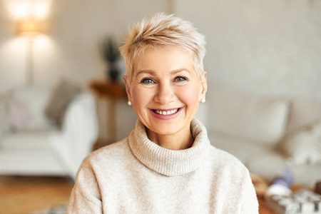 woman smiling after knowing what implant dentures are