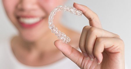 Woman holding up Invisalign aligner