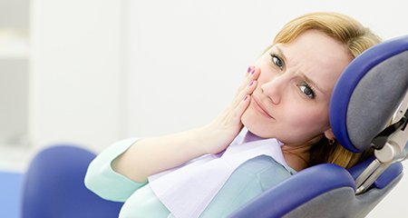 Woman at dental office for emergency dentistry holding jaw
