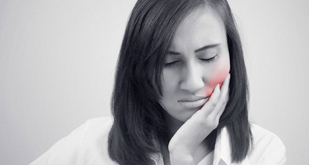 A woman holding her cheek in pain before root canal therapy