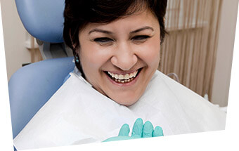 Smiling woman in dental chair after restorative dentistry treatment
