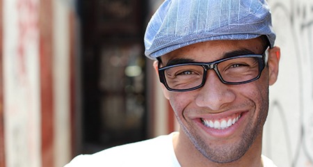 person smiling and leaning against a wall after six month smiles treatment