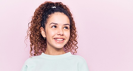 a teen with six month smiles clear braces smiling against a pink background