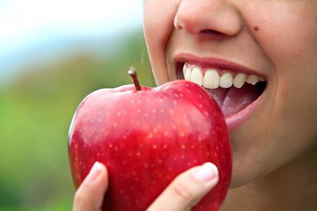 close up of person eating red apple after smile makeover