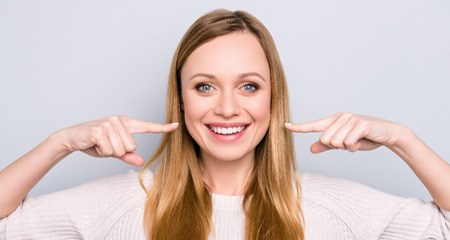 young woman pointing to her smile 