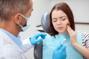 young woman seeing emergency dentist for painful tooth infection 