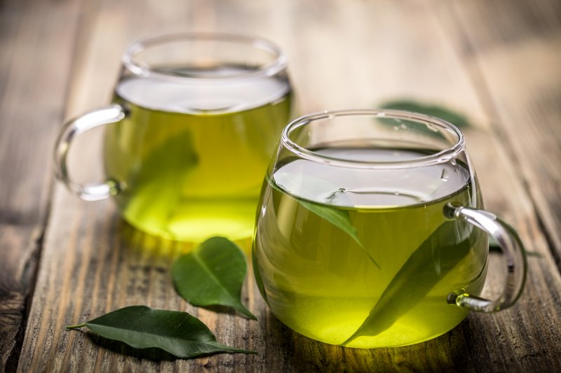 2 mugs of green tea sitting on a table