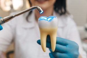 a dentist shining a light on a model of a tooth
