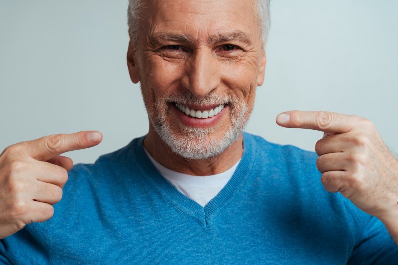 A handsome senior man pointing to his smile