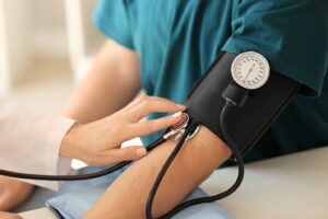 Doctor taking patient’s blood pressure with arm cuff.
